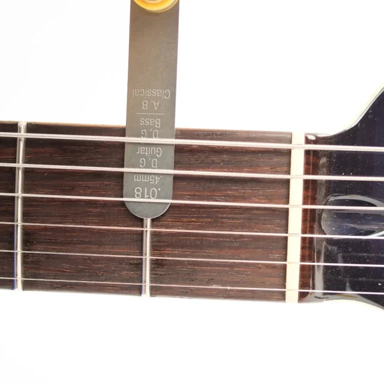 Music Nomad Precision Nut Height Gauge on guitar neck; silver metal tool with etched measurement marks