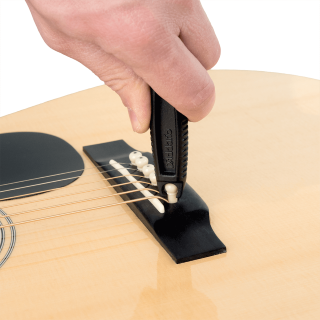 D'Addario Pro-Winder guitar string winder, black, in use on an acoustic guitar