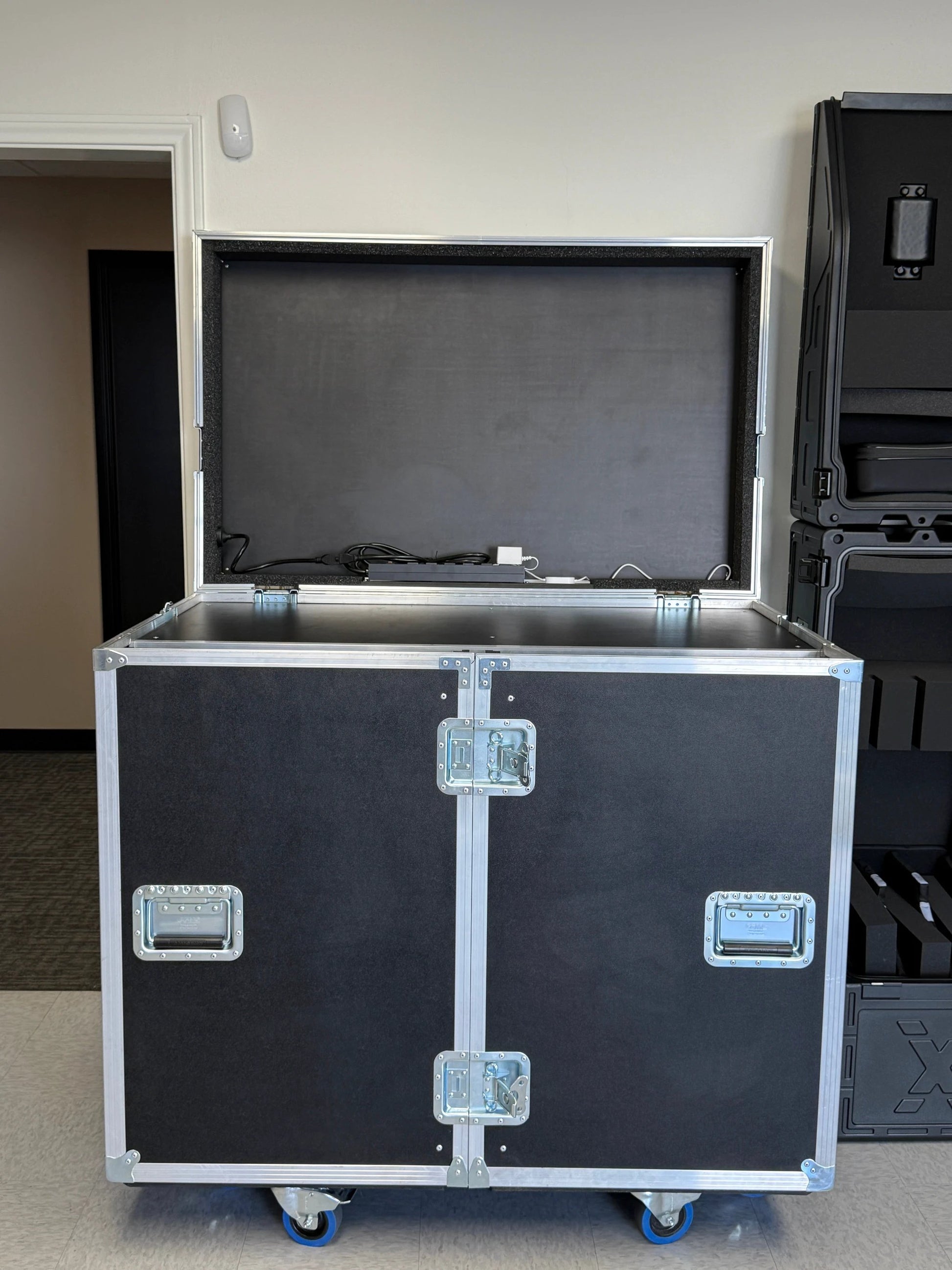 Black flight case workbox with open door on a gray floor